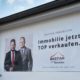 Werbeschild Bastian Immobilien Motiv mit Michael Bastian und Lucas Bastian